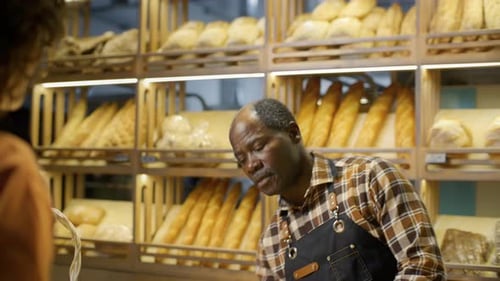 Friendly Bakery Worker Handing Freshly Baked Baguette to Customer