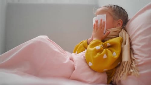Sick Girl Lying in Bed With Tissue