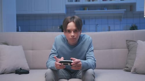 Boy plays video game on couch at night
