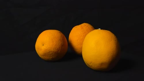 Three Ripe Oranges Against a Black Background