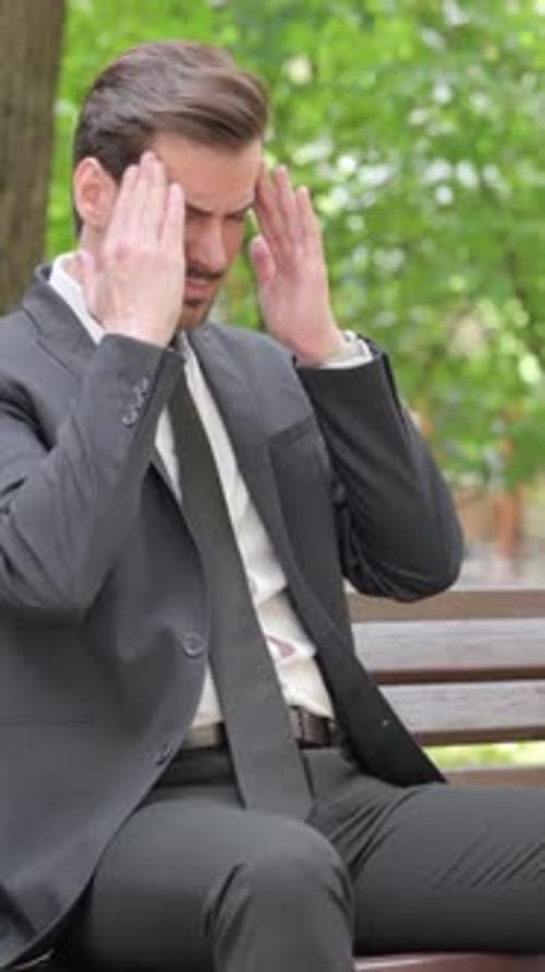 Worried man in a business suit sitting outside