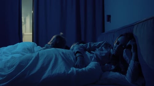 Baby and Woman Sleeping in Bed Together at Night