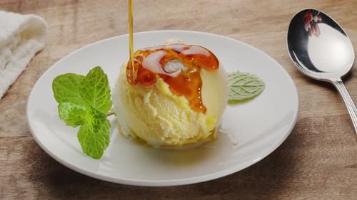 O xarope de caramelo é derramado em cima de uma bola de sorvete branco-amarela