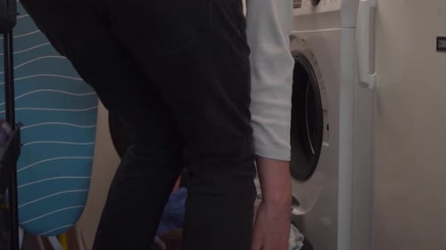Person Emptying Clothes from Front Loading Washing Machine
