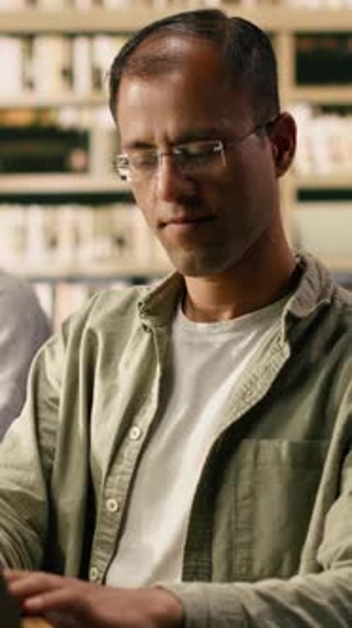 Vertical Video Smiling Adult Student Looks Away From Laptop in Quiet Library Study Area