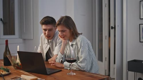 Young Couple Enjoying Laptop and Wine at Home