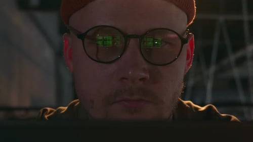 Le Code vert du programme se reflète dans les lunettes du programmeur