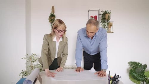 Architects Discussing a Blueprint in a Modern Office