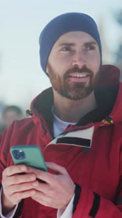 Man in Blue Hat Uses Smartphone and Smiles