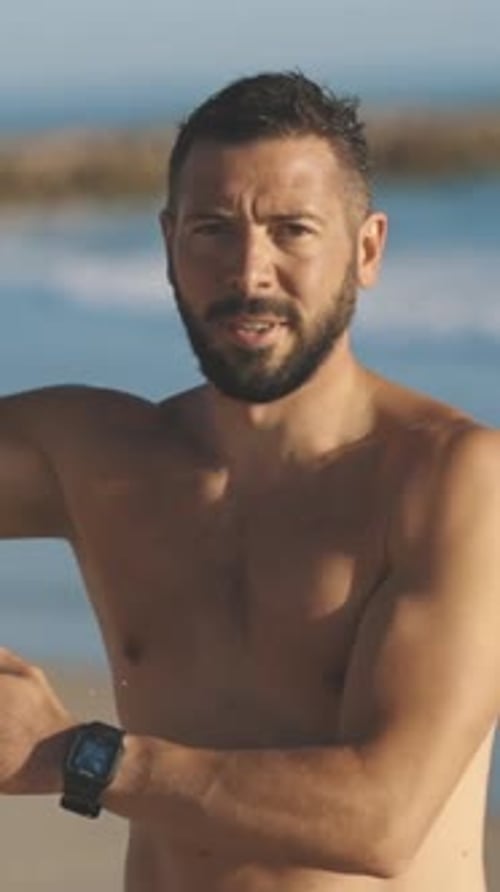 Bearded Man with Surfboard Gives Shaka Sign on Beach