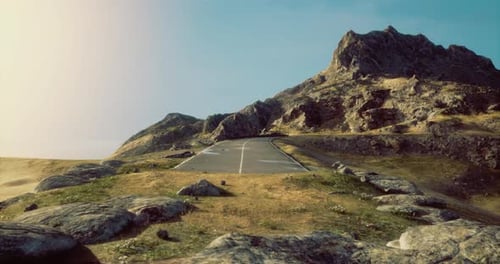 Road Winding Through Rocky Landscape Under Clear Sky in Daylight