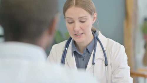 Female Doctor Talking with African Male Patient in Clinic