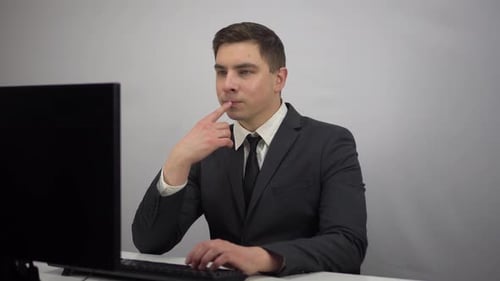 A Young Businessman is Sitting in the Office and Typing on a Computer Keyboard