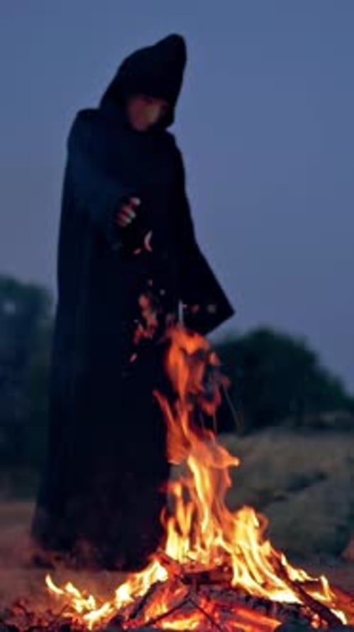 Figure in Cloak by Blazing Fire at Night