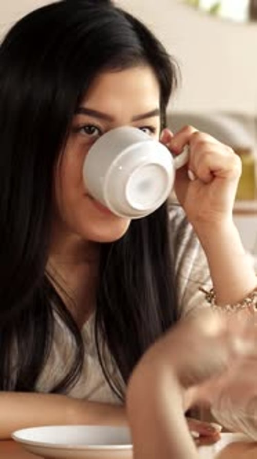 Woman with Dark Hair Drinks from Mug
