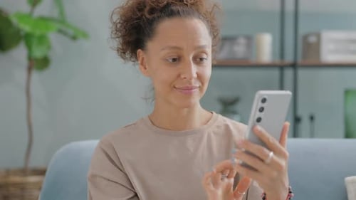 Woman Using Smartphone While Relaxing Indoors