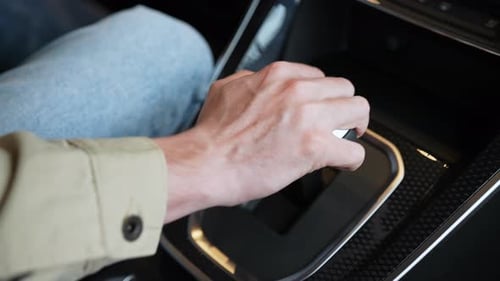 Vista superior de perto de um homem irreconhecível sentado no banco do motorista, mudando a transmissão automática em