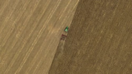 Aerial view of tractor tilling field, United Kingdom.