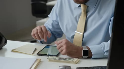 Clerk Counting Banknotes in Electronic Device Calculating on Tablet in Bank