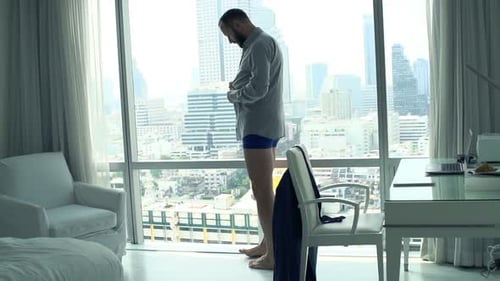 Man Dressing in Apartment with City View