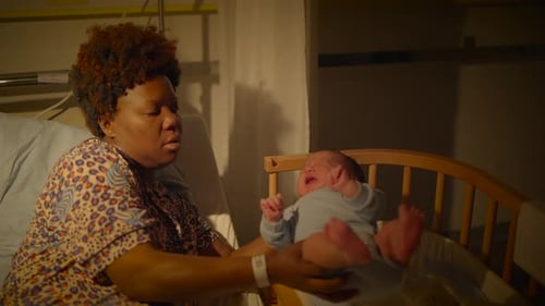 In the Hospital Crib a Mother Provides Comfort to Her Newborn Baby During the Night