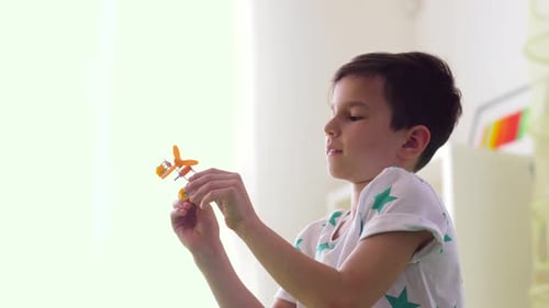 Young Boy Plays With Toy Airplane Indoors