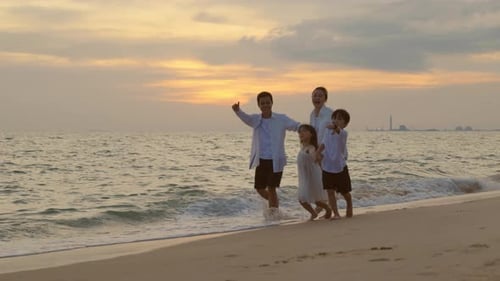 People of Father Mother Children Family of Four Holding Hands Together Walking on the Beach