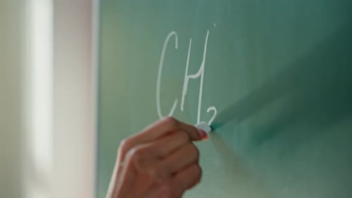 Close Up Female Hand Holding Chalk Writing Math Exercise on Blackboard Unrecognizable Student Girl