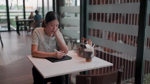 Die Frau sitzt alleine und genießt eine kreative Aktivität mit einem offenen Fenster in der Nähe.