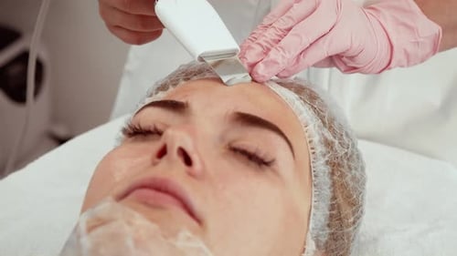 Professional Using Ultrasonic Facial Device During Skin Care Treatment at Aesthetic Center Non