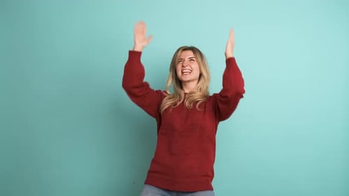 Woman Celebrates With Confetti in Front of Teal Wall