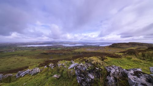 Timelapse of rural landscape with small rock formation in the foreground and hills and lake in