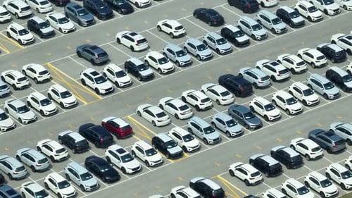Rows of a new cars parked in a distribution center, by drone aerial view.