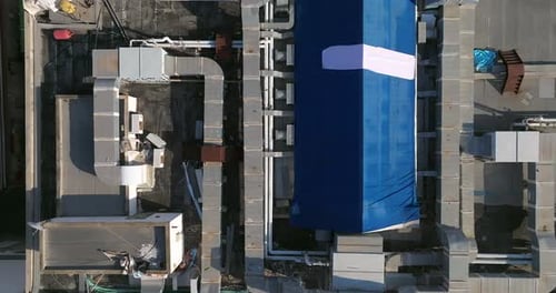 Industrial building rooftops with vents and pipes lined across, Top down view