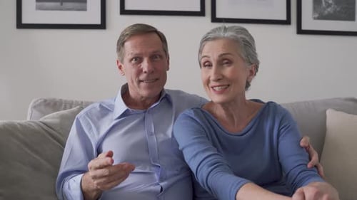 Cheerful senior couple talking on video call at home