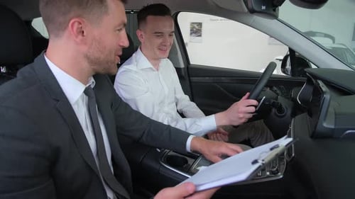 A Young Man is Talking to a Car Salesman A Guycustomer Buys a Vehicle in the Showroom