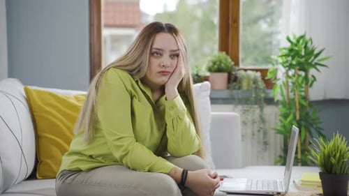 Sad Young Adult Sitting with Laptop Indoors