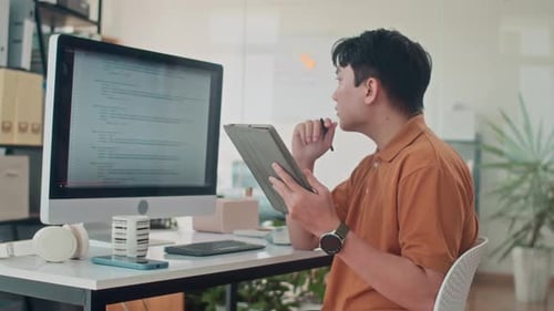 Focused Coder Working with Tablet at Desk