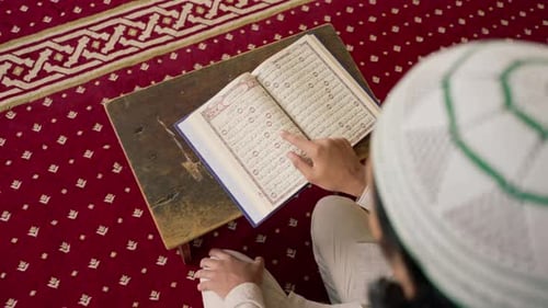Back view of a lonely Muslim man reciting the Holy Quran in mosque to heal his soul during Ramadan