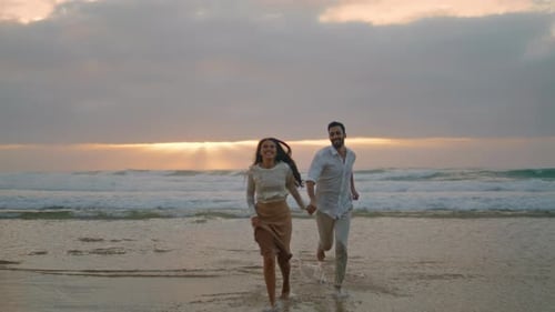 Ethnic lovers laughing running together on ocean beach sunset vacation