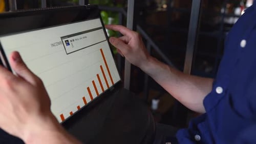 Man Analyzes Charts on Touchscreen Laptop