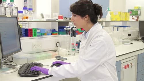 Female scientist working on computer and looks at screen in laboratory
