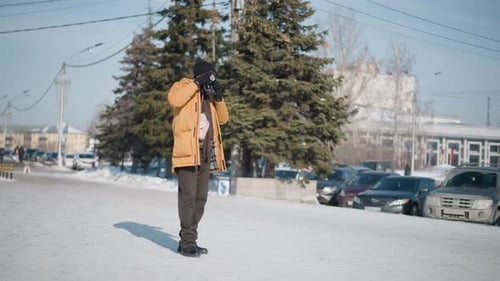 Photojournalist Adjusting Focus on Camera Viewfinder Street Under Winter Sun