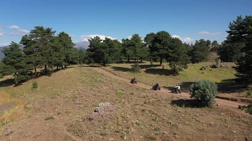 Aerial View Of Group Of People Riding On All Terrain Quadricycle Vehicle On Forest Road By Lake