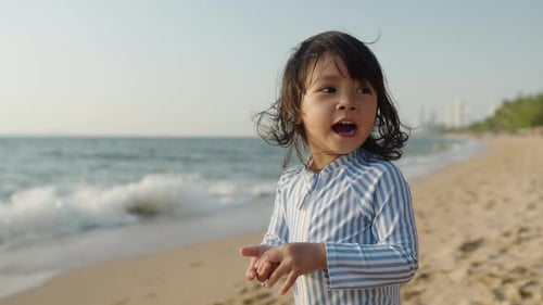 slow motion of cheerful toddler baby girl laughing on the sea beach in Pattaya, Thailand