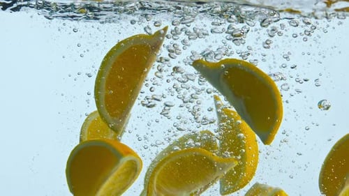 Fresh orange slices dropping into water splashing in super slow motion