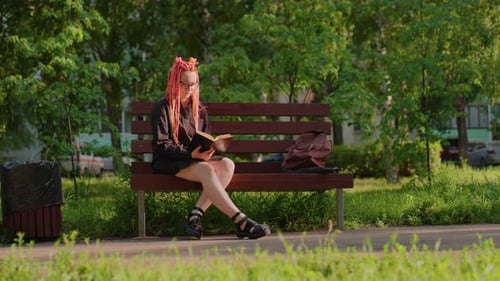Woman reading book on park bench outdoors