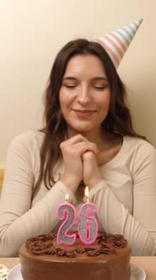 30. The girl is sitting in front of a table with a festive cake, in which a candle in the form of th