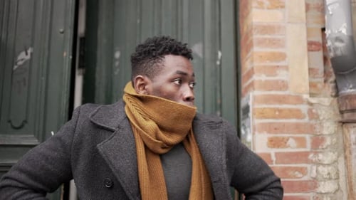 Man in Coat and Scarf Walks on Street