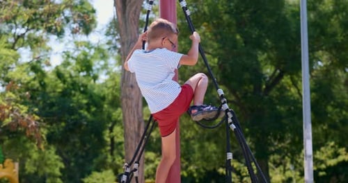 Boy Climbing Rope Structure at Outdoor Playground